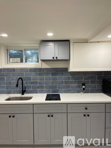A kitchen with white cabinets and a black faucet.