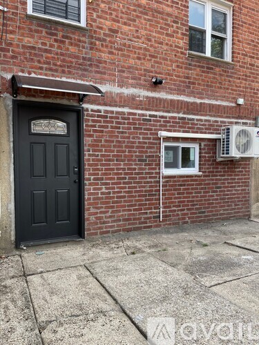 A black door is on the left side of a brick building.