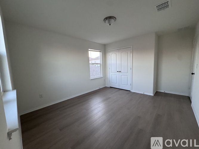 A spacious room with wooden flooring and white walls.