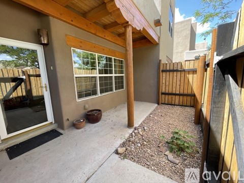 A patio area with a wooden pergola and a glass door.