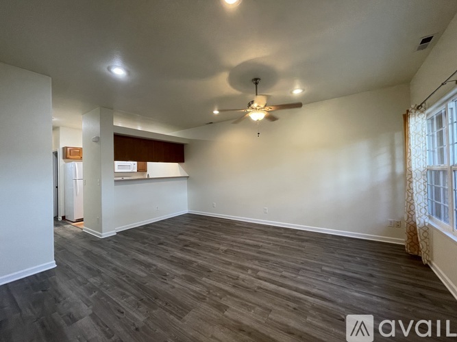 A spacious room with a ceiling fan and wood flooring.