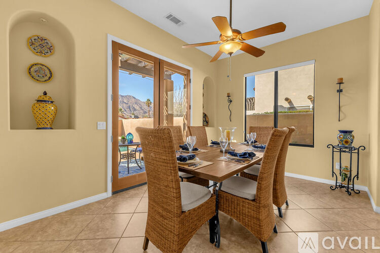A dining room with a table set for four and a fan.