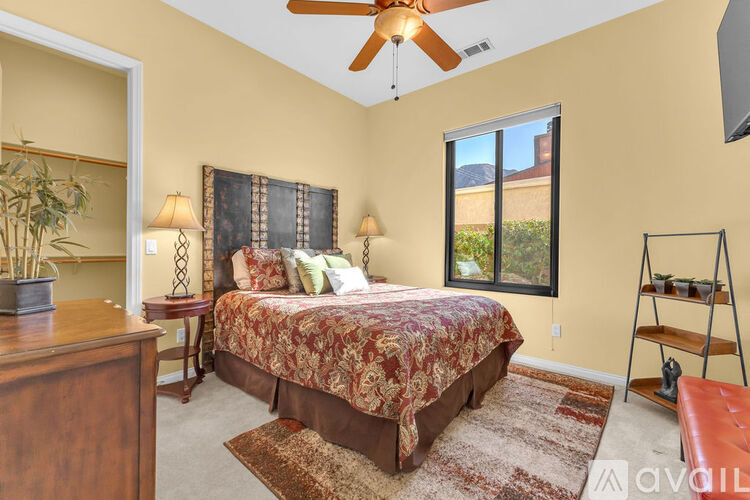 A bedroom with a bed, a dresser, a ceiling fan, and a window.
