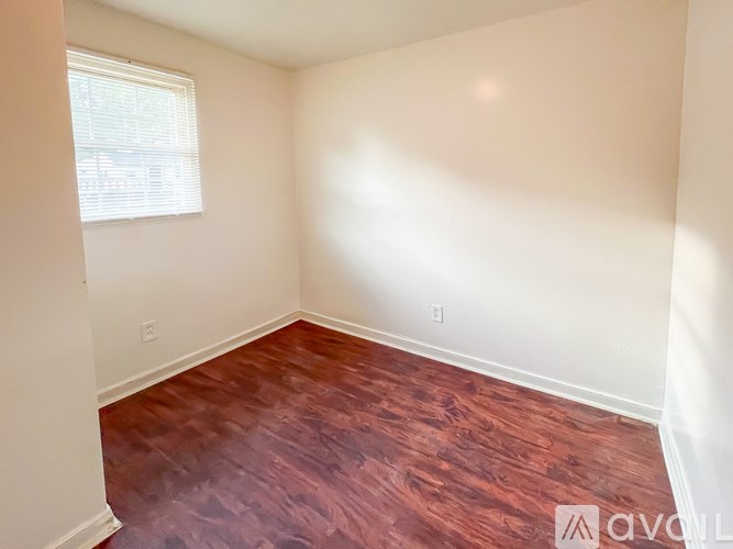 A room with wooden flooring and a window letting in sunlight.