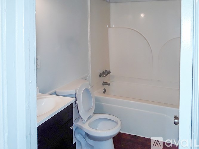 A white toilet in a small bathroom with a bathtub.