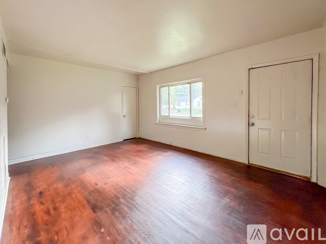 A room with wooden flooring and white walls.