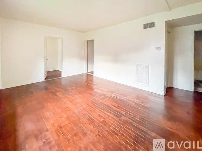 A room with wooden flooring and white walls.