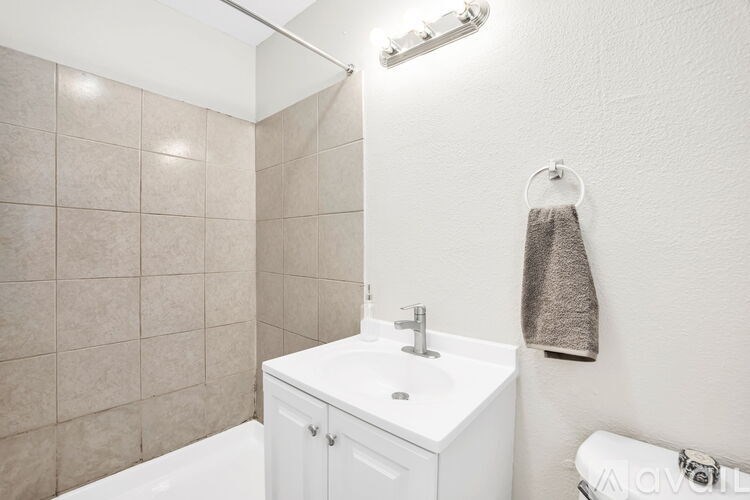 A white sink in a small bathroom with a towel hanging on the wall.