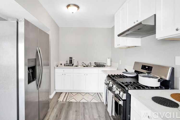 A modern kitchen with white cabinets and stainless steel appliances.