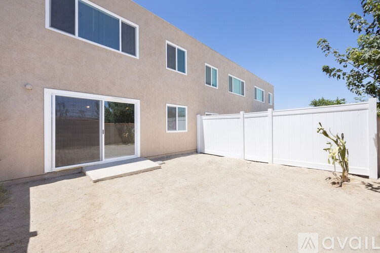 A modern house with a white fence and a tree in front.
