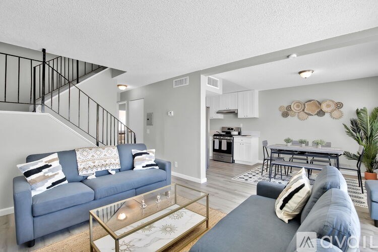A living room with a blue couch and a glass coffee table.