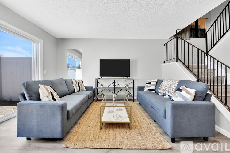 A living room with a grey couch, a coffee table, and a staircase.