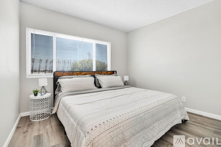 A bedroom with a large bed and a window with blinds.