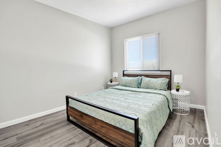 A bedroom with a bed, nightstand, and window.