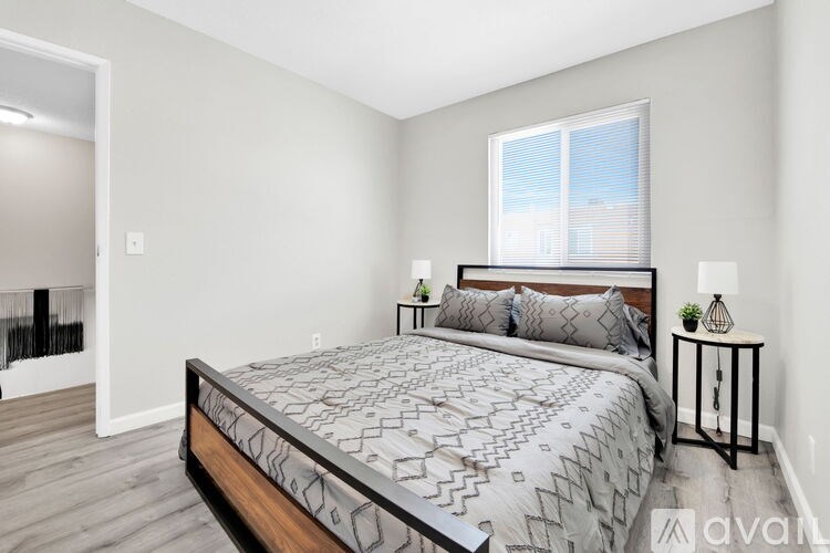 A bedroom with a large bed and a small table with a vase on it.