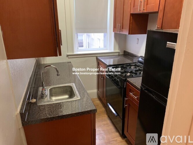 A kitchen with brown cabinets and a black refrigerator.