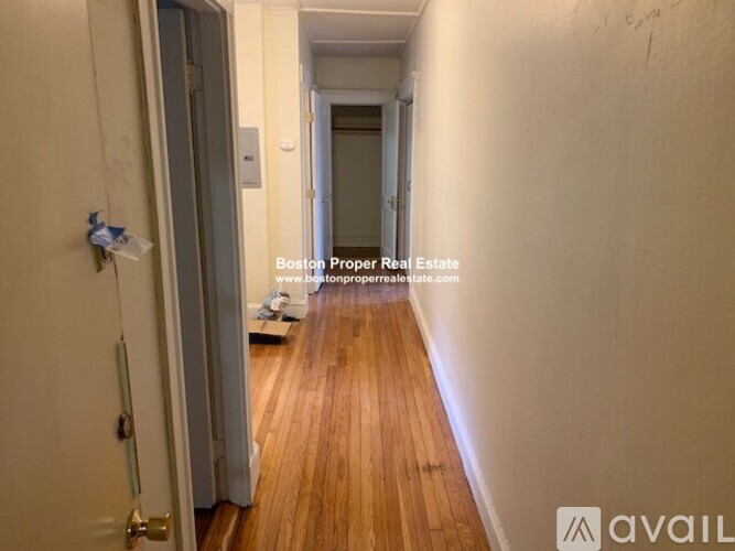 A hallway with wooden floors and white walls.