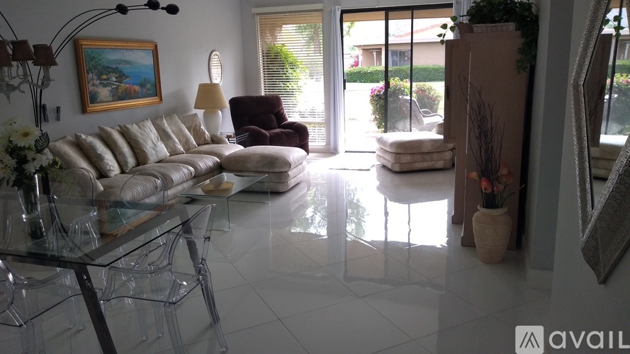 A living room with a glass table and a painting on the wall.