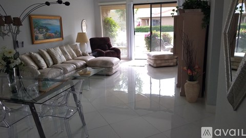 A living room with a glass table and a painting on the wall.