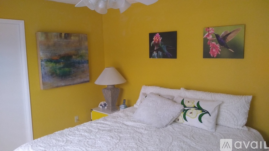 A bedroom with a white bed and two pictures on the wall.