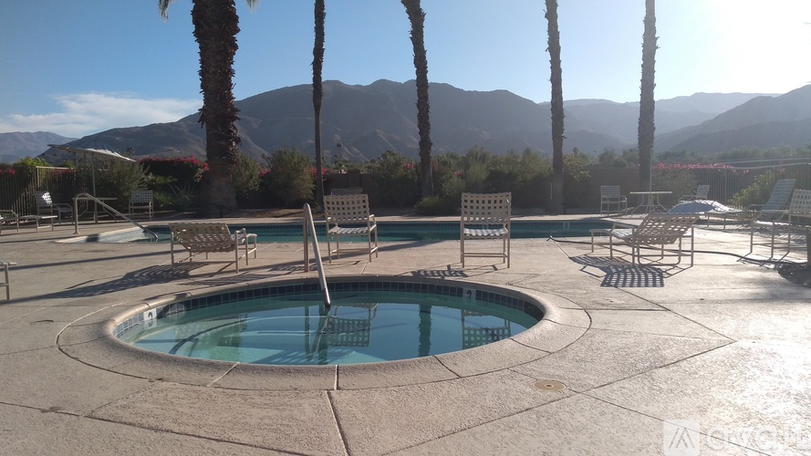 A pool surrounded by palm trees and mountains.