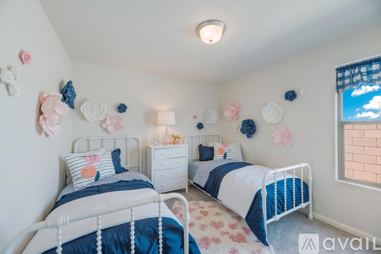 A bedroom with two beds, each with blue and white bedding, and decorative items on the wall.