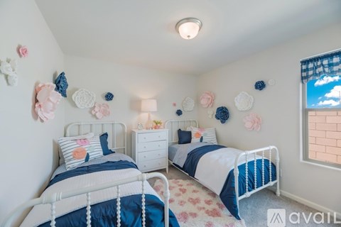A bedroom with two beds, each with blue and white bedding, and decorative items on the wall.