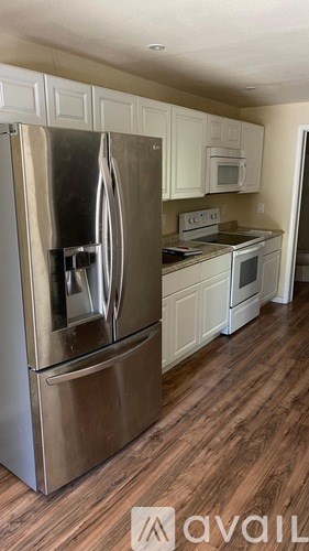 A kitchen with a stainless steel refrigerator and wooden floors.
