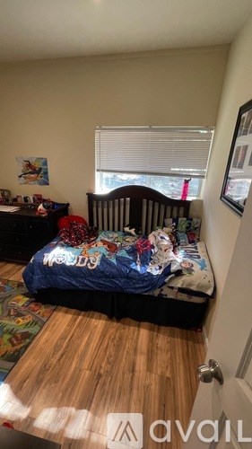 A child's bedroom with a bed, dresser, and a window with blinds.