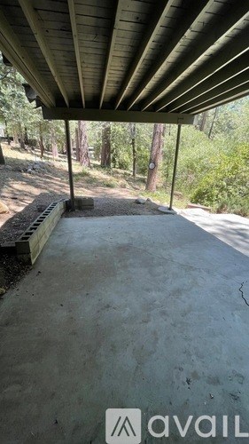 A patio with a concrete floor and a wooden roof.