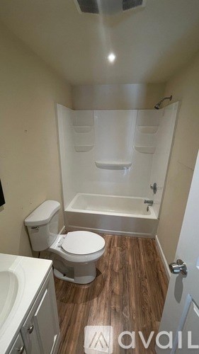 A white toilet sits in a small bathroom with a walk-in shower.