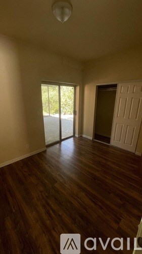 A room with wooden floors and a sliding glass door leading outside.