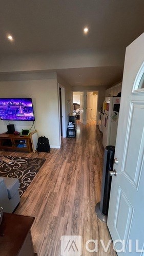 A hallway with a TV on the wall and a rug on the floor.