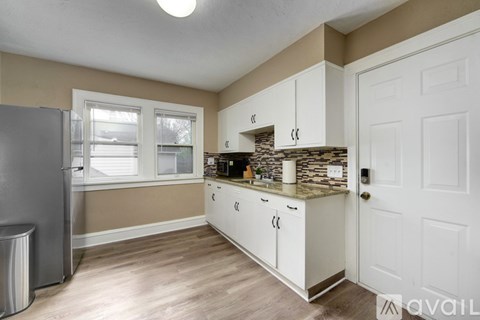 A kitchen with white cabinets and a stone backsplash.