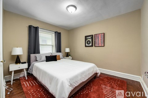 A bedroom with a white bed and a red rug.