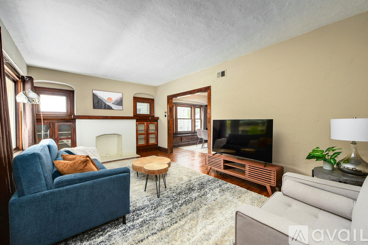 A living room with a blue couch, a fireplace, a television, and a rug.