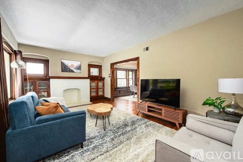 A living room with a blue couch, a fireplace, a television, and a rug.