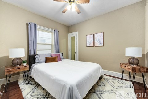 A bedroom with a bed, two lamps, and a ceiling fan.