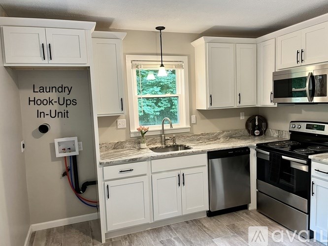 A kitchen with white cabinets and a sign that says "Laundry Hook-Ups In-Unit".