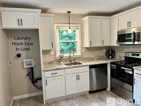 A kitchen with white cabinets and a sign that says "Laundry Hook-Ups In-Unit".