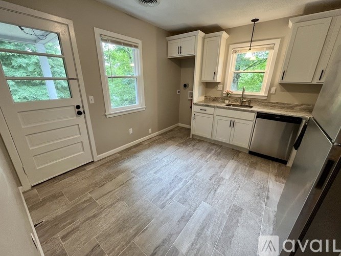 A kitchen with white cabinets and a wooden floor.