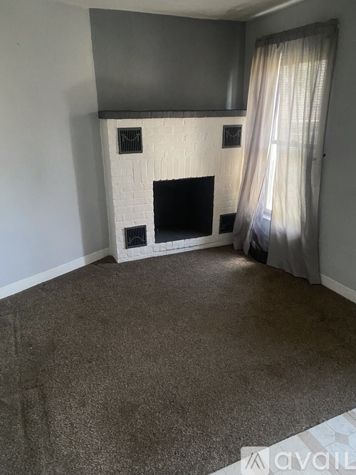 A living room with a fireplace and a grey carpet.
