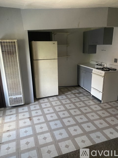 A kitchen with a white fridge, white stove, and a white tile floor.
