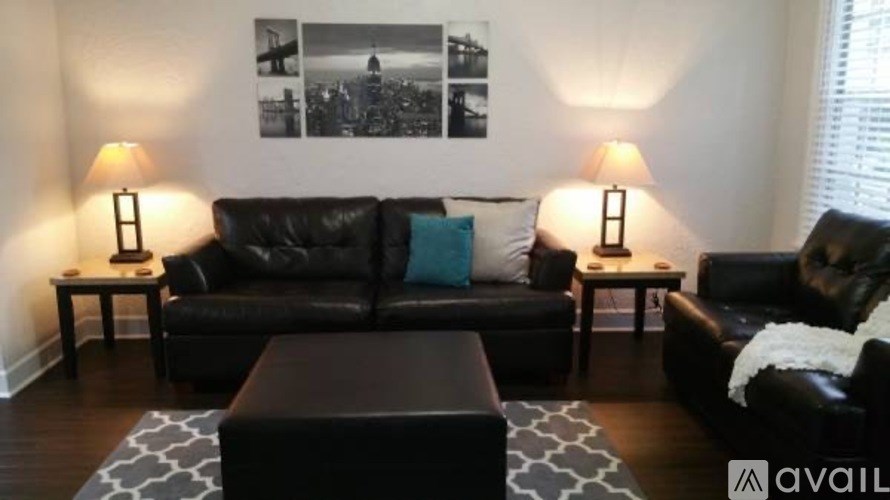 A black leather couch with a blue pillow and two lamps on side tables.