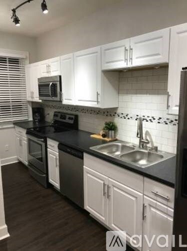 A kitchen with white cabinets and black countertops.