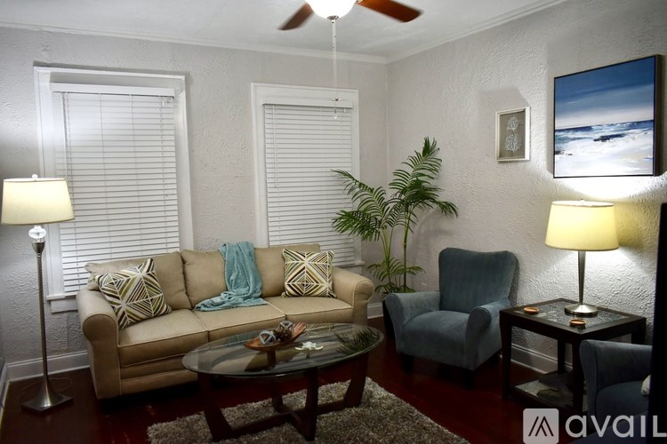 A living room with a couch, chair, and a table with a lamp on it.