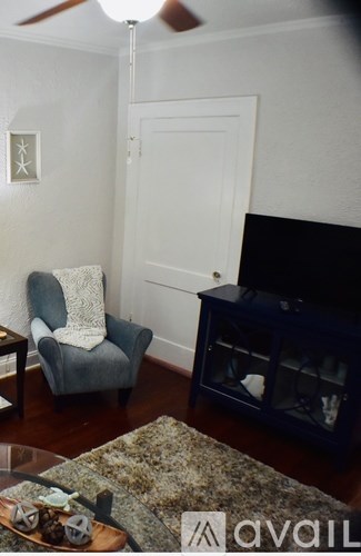 A living room with a grey chair and a black fireplace.
