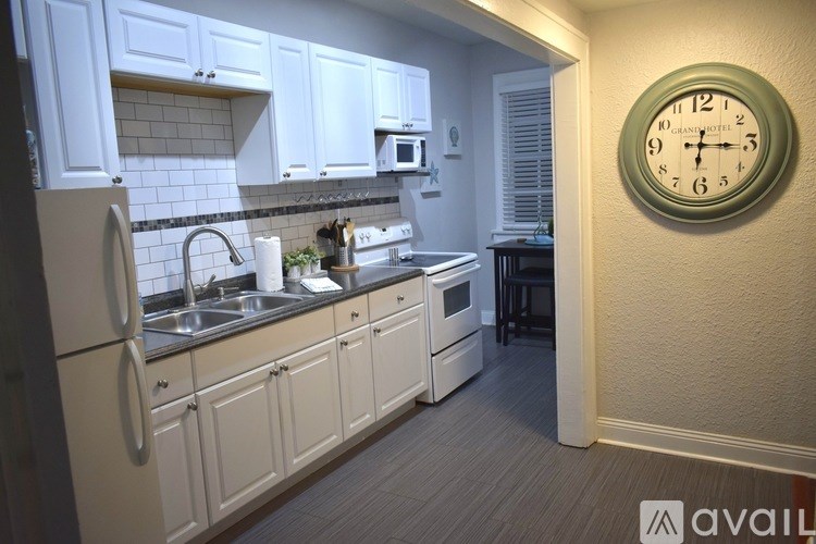 A kitchen with white cabinets and a clock on the wall.