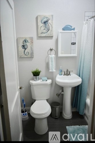 A small bathroom with a toilet, sink, and two pictures on the wall.