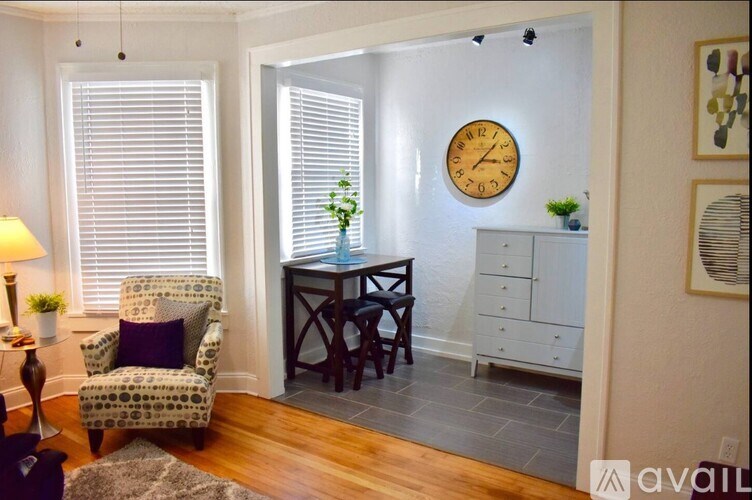 A living room with a chair, a table, a clock, and a cabinet.